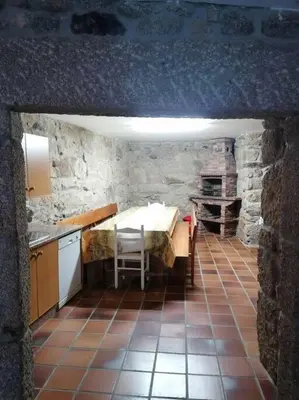 a kitchen with a table in a stone building at O Lar do Suso in Refojos