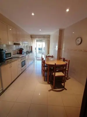a kitchen with a table and chairs and a clock on the wall at O Lar do Suso in Refojos