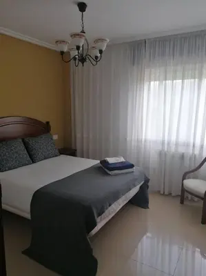 a bedroom with a bed and a window with a chair at O Lar do Suso in Refojos