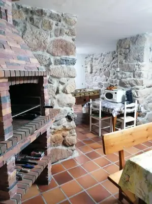 a living room with a stone fireplace and a table at O Lar do Suso in Refojos