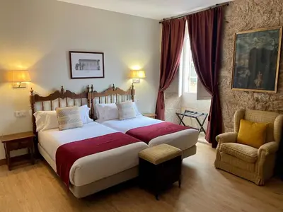 a bedroom with a large bed and a chair at Hotel Pazo de Bieite in Boimorto