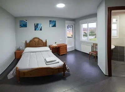 a bedroom with a large bed and a bathroom at Hostal Molgas in A Medorra