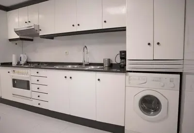 a white kitchen with a sink and a washing machine at Apartamento en Sigüeiro Rúa do Tambre in Sigüeiro