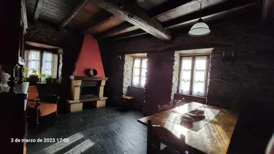 a dining room with a wooden table and windows at Apartamentos Rurales Casa Ardaliz in Cangas del Narcea