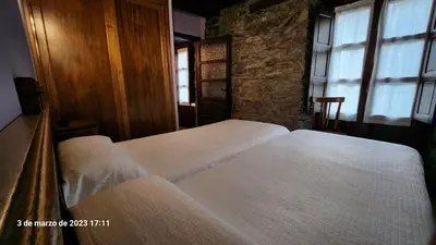 a bedroom with two beds and a window at Apartamentos Rurales Casa Ardaliz in Cangas del Narcea