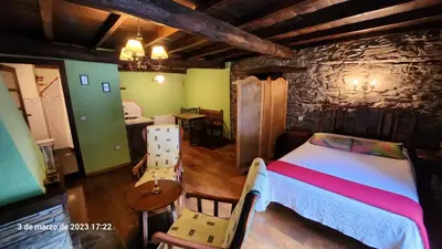 a bedroom with a bed and a table and chairs at Apartamentos Rurales Casa Ardaliz in Cangas del Narcea