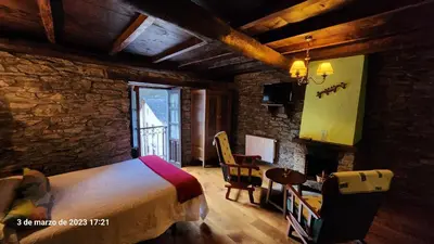 a bedroom with a bed and a table and a chair at Apartamentos Rurales Casa Ardaliz in Cangas del Narcea