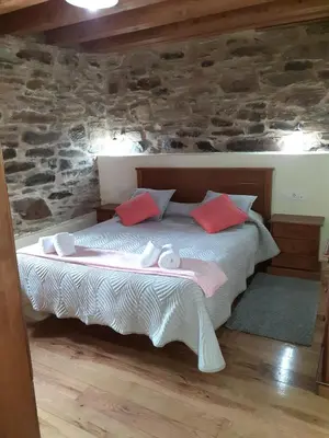 a bedroom with a bed in a stone wall at O Busto Aldea Rural, Apartamento HORNO 1 in Puebla del Brollón