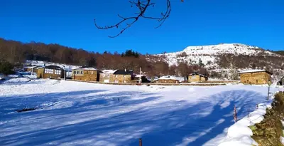 a snow covered field with houses and a mountain at O Busto Aldea Rural, Apartamento HORNO 1 in Puebla del Brollón