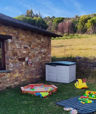 a backyard with a sandbox and toys in the grass at O Busto Aldea Rural, Apartamento HORNO 2 in A Pobra do Brollon