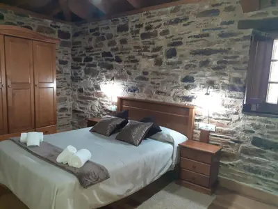 a bedroom with a bed and a stone wall at O Busto Aldea Rural, Apartamento HORNO 2 in A Pobra do Brollon