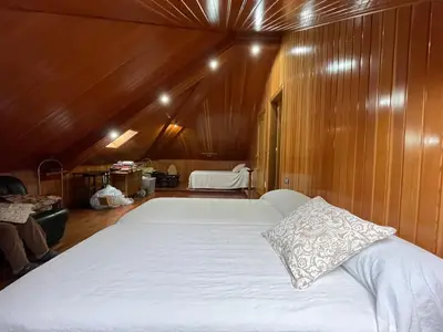 a large white bed in a room with wooden walls at Impresionante casa con parcela en la naturaleza in A Coruña