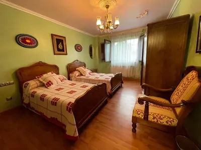 a bedroom with two beds and a chair and a chandelier at Impresionante casa con parcela en la naturaleza in A Coruña