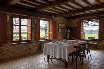 a dining room with a table with chairs and windows at Casa A Curiscada in Burres