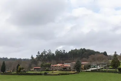 a green field with houses and trees in the background at Casa A Curiscada in Burres