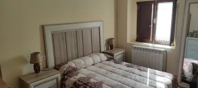 a bedroom with a bed and two tables and a window at Casa Ángel in Barreiros