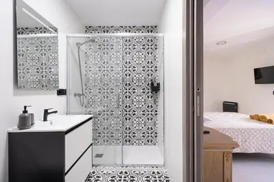 a bathroom with a shower and a sink next to a bed at Luxury Barco de Valdeorras in Vegamolinos
