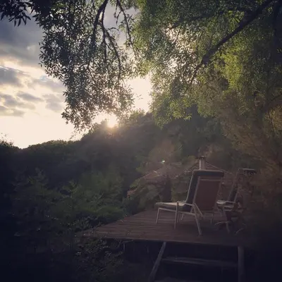 two chairs sitting on a wooden deck with the sun setting at O Muíño da Balsiña in Tuiriz