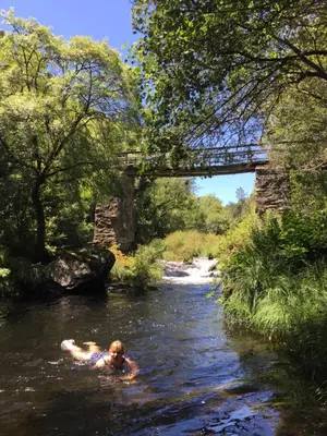 a person swimming in a river under a bridge at O Muíño da Balsiña in Tuiriz