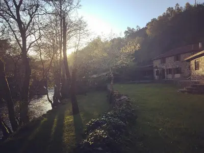 a view of a yard with a house and a river at O Muíño da Balsiña in Tuiriz