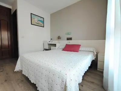 a bedroom with a white bed with a red pillow on it at Nest El Camino in Santiago de Compostela
