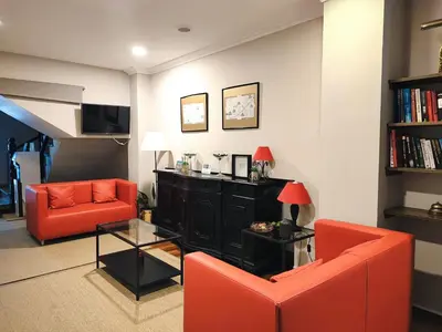 a living room with two orange chairs and a black cabinet at Nest El Camino in Santiago de Compostela