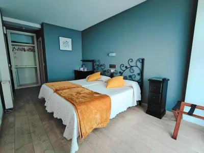 a blue bedroom with a bed with orange pillows at Nest El Camino in Santiago de Compostela
