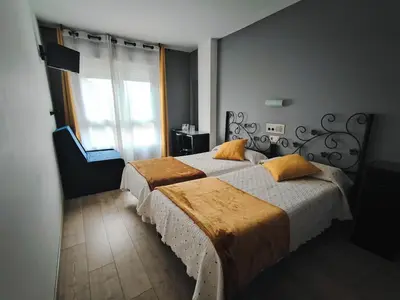 a bedroom with two beds and a large window at Nest El Camino in Santiago de Compostela