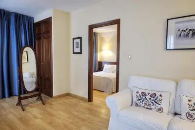 a living room with a couch and a bedroom at Hotel y Apartamentos Arias in Navia