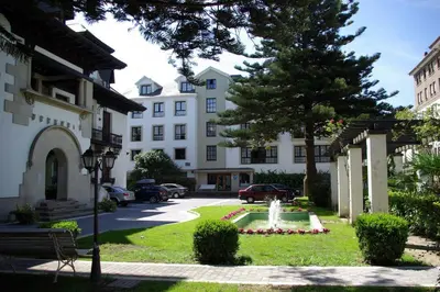 a park in front of a building with a fountain at Hotel y Apartamentos Arias in Navia