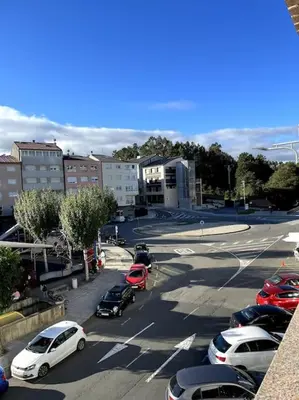 a parking lot with cars parked in a city at El apartamento de Ordes in Órdenes