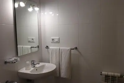 a white bathroom with a sink and a mirror at PENSIÓN RÚA in Arzúa