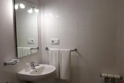 a white bathroom with a sink and a mirror at PENSIÓN RÚA in Arzúa