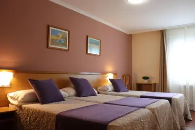 two beds in a hotel room with purple walls at PENSIÓN RÚA in Arzúa