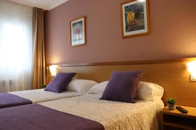 a hotel room with two beds with purple pillows at PENSIÓN RÚA in Arzúa