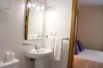 a white bathroom with a sink and a mirror at PENSIÓN RÚA in Arzúa