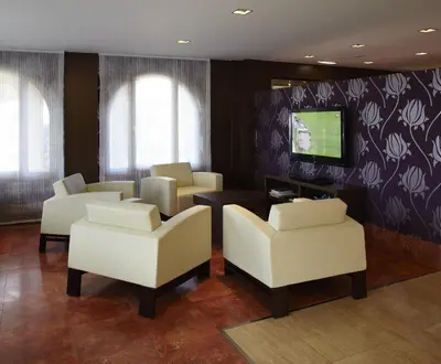 a waiting room with white chairs and a tv at Blanco Hotel Spa in Navia