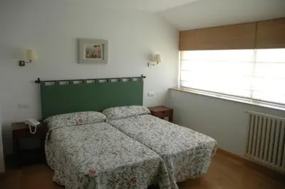 a bedroom with a bed with a green headboard and a window at Casa Grande da Capellania in Padrón