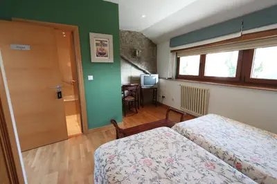 a bedroom with two beds and a door and a table at Casa Grande da Capellania in Padrón