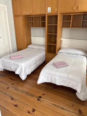 two beds in a room with wooden floors and cabinets at PR Paz de Agra in Santiago de Compostela
