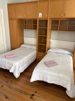 two beds in a room with wooden cabinets at PR Paz de Agra in Santiago de Compostela