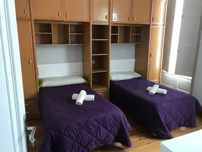 two beds in a room with purple sheets at PR Paz de Agra in Santiago de Compostela