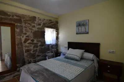 a bedroom with a bed and a stone wall at Casa Avoa María in Ourense