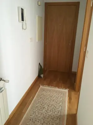 a hallway with a wooden door and a rug at Alquiler de piso nuevo in Burela de Cabo