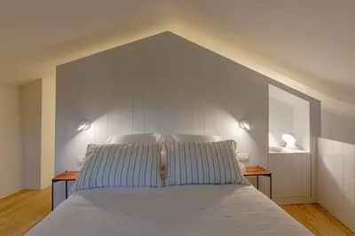 a bedroom with a bed with two lights on the wall at A casa de Abaixo, aloxamento rural in Vedra