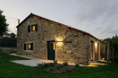 a stone house with a green door in a yard at A casa de Abaixo, aloxamento rural in Vedra