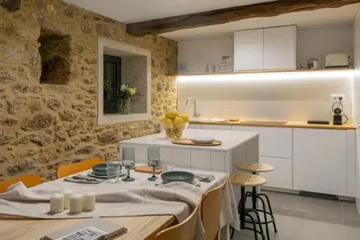 a kitchen with white cabinets and a table and chairs at A casa de Abaixo, aloxamento rural in Vedra