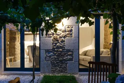 a living room with a couch and a stone wall at A casa de Abaixo, aloxamento rural in Vedra