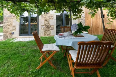 a table and chairs under a tree in a yard at A casa de Abaixo, aloxamento rural in Vedra