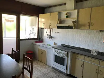 a kitchen with a stove and a sink and a table at Piso grande y muy luminoso in Santiago de Compostela